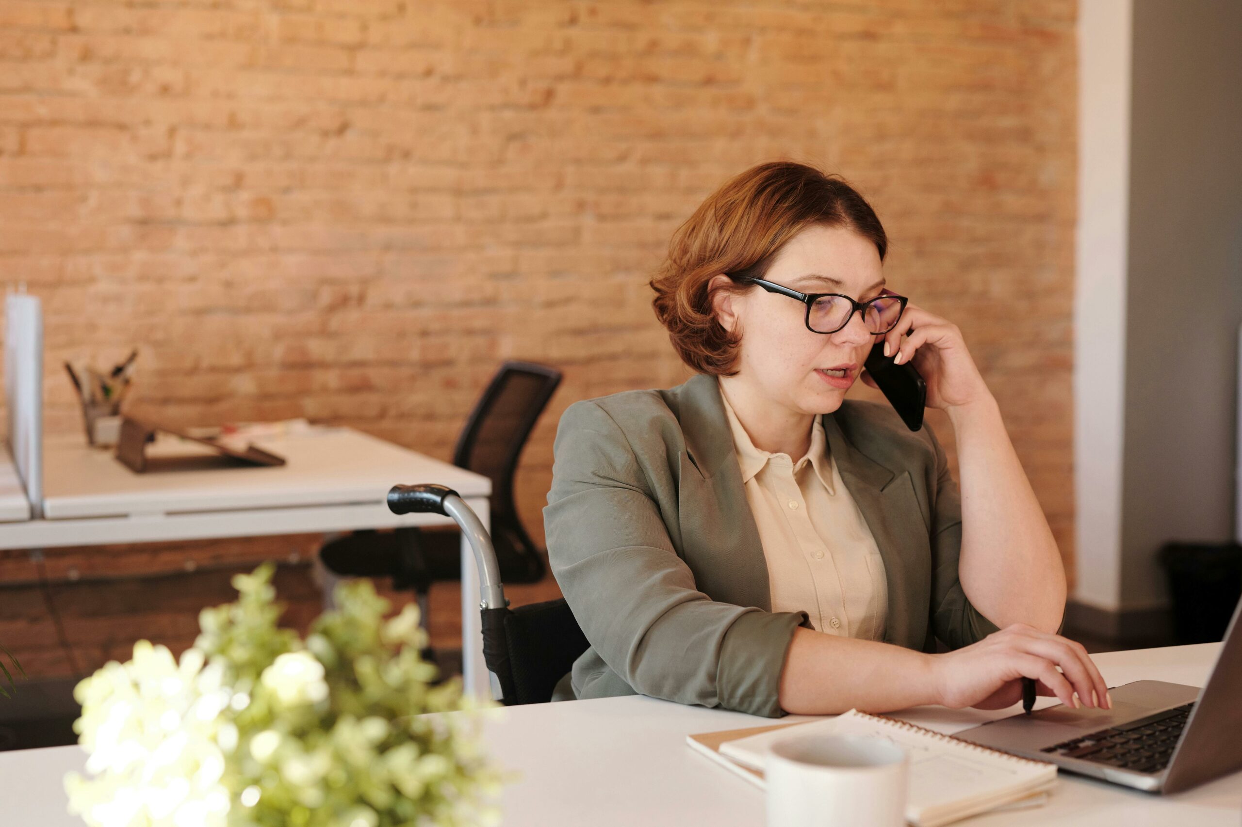 Photo of woman talking through smartphone while using laptop